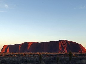 In this Tuesday, April, 22, 2014, file photo, the sun rises over Uluru, Australia. Climbing the dramatic rock formation will be banned in two years after declining visitors to the Australian scenic landmark increasingly recognize its sacredness.