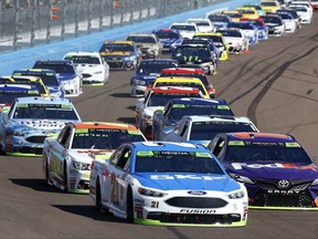 Ryan Blaney (21) leads a group of drivers into the first turn during a NASCAR Cup Series auto race at Phoenix International Raceway, Sunday, Nov. 12, 2017, in Avondale, Ariz. (AP Photo/Ross D. Franklin)