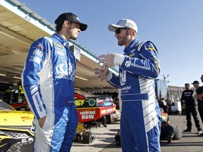 Dale Earnhardt Jr., right, talks with Trevor Bayne in the garage area before practice for the NASCAR Cup Series auto race at Phoenix International Raceway, Saturday, Nov. 11, 2017, in Avondale, Ariz. Sunday's race will be Earnhardt's final race in Phoenix as he plans to retire after the 2017 season. (AP Photo/Ralph Freso)