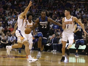 Minnesota Timberwolves forward Andrew Wiggins (22) drives between Phoenix Suns guard Mike James and Devin Booker (1) in the first half during an NBA basketball game, Saturday, Nov 11, 2017, in Phoenix. (AP Photo/Rick Scuteri)