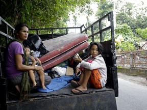 Villagers sit with their belongings on a truck during an evacuation in Karangasem, Bali, Indonesia, Thursday, Nov. 30, 2017. Authorities have told tens of thousands of people to leave an area extending 10 kilometers (6 miles) from the volcano as it belches volcanic materials into the air. Mount Agung's last major eruption in 1963 killed about 1,100 people. (AP Photo/Firdia Lisnawati)