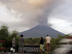 Tourists watch the Mount Agung volcano erupting in Karangasem, Indonesia, Monday, Nov. 27, 2017. Indonesia authorities raised the alert for the rumbling volcano to highest level on Monday and closed the international airport on tourist island of Bali stranding thousands of travelers. (AP Photo/Firdia Lisnawati)