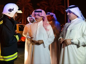 In this photo released by Bahrain News Agency, Sheikh Rashid bin Abdullah Al Khalifa, Bahrain Minister of Interior talks with a member of the emergency services, during his visit to the scene of an explosion, in Bahrain, Saturday, Nov. 11, 2017.  Bahrain says an oil pipeline that exploded overnight was attacked by militants in the island nation. (Bahrain News Agency via AP)