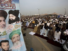 Supporters of Pakistani religious radical party Tehreek-i-Labaik Ya Rasool Allah offer Friday prayers with a poster of their leaders, during a sit-in protest in Islamabad, Pakistan, Friday, Nov. 10, 2017. Hundreds of Islamists have camped out on the edge of Pakistan's capital to demand the removal of the country's law minister over a recently omitted reference to the Prophet Muhammad in a constitutional bill. (AP Photo/B.K. Bangash)