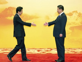 FILE - In this Nov. 11, 2014, file photo, Japan's Prime Minister Shinzo Abe reaches out to shake hands with Chinese President Xi Jinping during a regional economic meeting in Yanqi Lake, Beijing. Asia's two major regional meetings are unfolding in coming days, filling the news cycles with imagery of groups of political luminaries greeting and meeting, its usually in the "bilats" – the "bilateral meetings " between ministers or leaders that take place on the sidelines of meetings like APEC and ASEAN, both of which are happening late this week and early next. (AP Photo/Ng Han Guan, File)