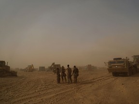 In this Monday, Nov. 6, 2017 photo, U.S. Marines build a military site during a sandstorm in western Anbar, Iraq. The US-led coalition's newest outpost in the fight against the Islamic State group is in this dusty corner of western Iraq near the border with Syria where several hundred American Marines operate close to the battlefront, a key factor in the recent series of swift victories against the extremists. (AP Photo/Khalid Mohammed)