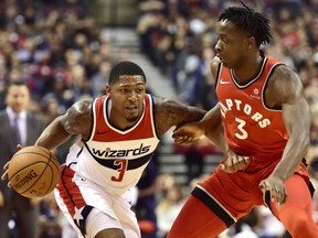 Washington Wizards guard Bradley Beal ,left, dribbles the ball under pressure as Toronto Raptors forward OG Anunoby defends during the second half in Toronto on Sunday.