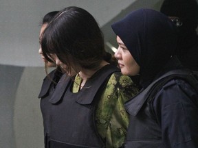 FILE - In this Wednesday, Nov. 29, 2017, file photo, Vietnamese Doan Thi Huong, center, is escorted by police as she leaves the Shah Alam court house after her trial in Shah Alam, outside Kuala Lumpur, Malaysia. Prosecutors have focused on proving the women's guilt but shied away from scrutinizing any political motive behind the killing. Defense lawyers, who say their clients were duped into carrying out the attack, will look to shift that focus when the trial resumes Jan. 22. (AP Photo/Sadiq Asyraf, File)