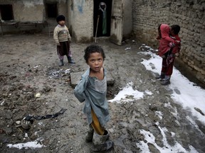 FILE - In this Wednesday, Feb. 19, 2014, file photo, Afghan internally displaced children stand in a muddy yard at a poor neighborhood in Kabul, Afghanistan. A United Nations report says the world's least developed countries need access to electricity if they are to break out of poverty. It says 60 percent of people in the world's poorest countries have no access to electricity _ some 577 million people in total. (AP Photo/Massoud Hossaini, File)