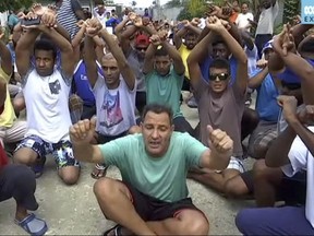 FILE - In this file photo made from Australia Broadcasting Coporation video made on Tuesday, Oct. 31, 2017, asylum seekers protesting the possible closure of their detention center, on Manus Island, Papua New Guinea. An official Wednesday, Nov. 8, 2017, says more than 500 asylum seekers remain in a decommissioned Australian immigration camp in Papua New Guinea after a court ruled authorities no longer have to supply power, food and water.  (Australia Broadcasting Corporation via AP, File)