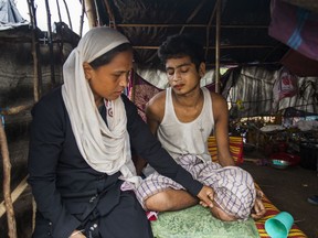 In this Oct. 12, 2017, photo, Zahida Begum, left, listens to a Rohingya boy who she helped escape to Bangladesh as she visits him in Thangkhali, Cox's Bazar, Bangladesh. Zahida Begum was only 18 months old when her mother, fleeing Muslim Rohingya persecution in Myanmar, smuggled her in a fishing boat into Bangladesh. When frantic relatives called her in late September to tell her that Myanmar soldiers were burning Rohingya villages and tens of thousands of Rohingya were fleeing, she jumped into action, making calls and raising money to arrange boats to bring 400 people to safety. (AP Photo/Salahuddin Ahmed)