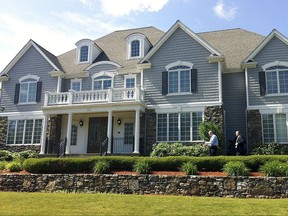 FILE - In this June 19, 2013 file photo, two members of the Massachusetts State Police walk toward the front door of the home of New England Patriot's NFL football player Aaron Hernandez in North Attleborough, Mass. The home was sold in November 2017 to 23-year-old real estate investor Arif Khan for $1 million, about $300,000 lower than the asking price. (AP Photo/Erika Niedowski, File)