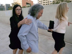 FILE - In this Oct. 26, 2017 file photo, Insys Therapeutics founder John Kapoor, center, is escorted from U.S. District Court in Phoenix. He had been charged with leading a conspiracy to bribe doctors to prescribe an opioid pain medication for people who didn't need it. Kapoor is scheduled for arraignment Thursday, Nov. 16, in federal court Boston. (AP Photo/Ross D. Franklin, File)