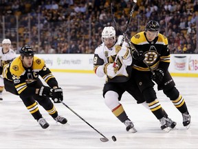 Boston Bruins defenseman Zdeno Chara reaches in for the puck as teammate Charlie McAvoy, right, battles Vegas Golden Knights' James Neal during the first period of an NHL hockey game in Boston, Thursday, Nov. 2, 2017. (AP Photo/Winslow Townson)