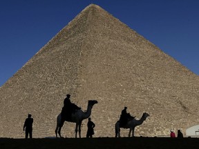 FILE - In this Dec. 12, 2012 file photo, policemen are silhouetted against the Great Pyramid in Giza, Egypt. Scientists have found a previously undiscovered hidden chamber in Egypt's Great Pyramid of Giza, the first such discovery in the structure since the 19th century. In a report published in the journal Nature on Thursday, Nov. 2, 2017, an international team says the 30-meter (yard) void deep within the pyramid is situated above the Grand Gallery, and has a similar cross-section. (AP Photo/Hassan Ammar, File)