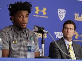 UCLA head coach Steve Alford, right, listens as Jalen Hill reads his statement during a news conference at UCLA Wednesday, Nov. 15, 2017, in Los Angeles. Three UCLA NCAA college basketball players accused of shoplifting in China admitted to the crime and apologized before coach Steve Alford announced they were being suspended indefinitely. (AP Photo/Jae C. Hong)