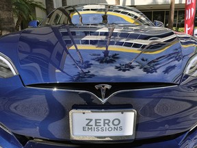 In this Oct. 24, 2016, file photo, palm trees are reflected on the hood of a Tesla Model S on display in downtown Los Angeles.