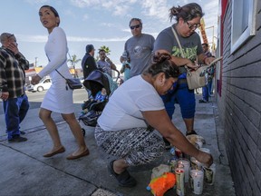 People gather at a makeshift memorial on the corner of Indiana Street and Whittier Blvd. in Boyle Heights, Friday, Nov. 17, 2017, where two boys were killed after they were struck by a Los Angeles County Sheriff's Department vehicle that was involved in a crash while responding to a radio call of shots fired. One of the boys died at the scene and the other at a hospital. Their mother was critically injured. (Irfan Khan/Los Angeles Times via AP)