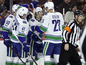 Vancouver Canucks' Brock Boeser, centre, celebrates with his teammates after scoring a goal during the first period against the Flyers on Tuesday night in Philadelphia. The Canucks won 5-2.