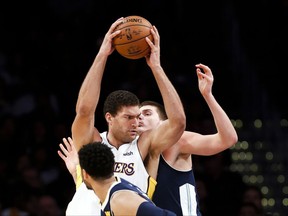 Los Angeles Lakers center Brook Lopez, center, drives against Denver Nuggets center Nikola Jokic, right, of Serbia during the first half of an NBA basketball game, Sunday, Nov. 19, 2017, in Los Angeles. (AP Photo/Ringo H.W. Chiu)
