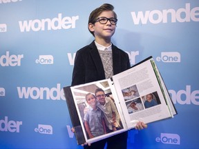 Jacob Tremblay, star of the movie "Wonder" holds a binder, containing letters written to him to help him prepare for his role, as he attends attends an event at Toronto's Sick Kids Hospital, in Toronto on Monday November 20, 2017. Vancouver child actor Jacob Tremblay was in Toronto on Monday for a special screening of his new film "Wonder" about a child with facial deformities -- sharing it with a group of young patients who live that reality every day and helped him prepare for his role. The 11-year-old plays Auggie Pullman, a child with Treacher Collins syndrome, a rare congenital condition in which babies are born with underdeveloped facial bones and often little or no external ears. THE CANADIAN PRESS/Chris Young