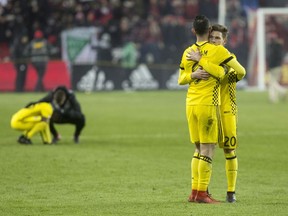 Columbus Crew midfielder Will Trapp (20) consoles forward Justin Meram (9) at the final whistle as Toronto FC wins the MLS Eastern Conference final 1-0 to progress to the MLS Cup final in Toronto on Wednesday, November 29, 2017. THE CANADIAN PRESS/Chris Young