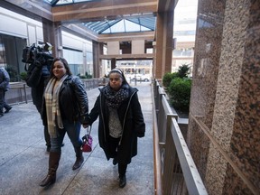 Francie Munoz, right, holds her sister Yasmin Munoz's hand as she walks with family into the Toronto Police headquarters on Tuesday, November 28, 2017. Two Toronto police officers caught on tape mocking a 29-year-old woman with Down syndrome are expected to plead guilty to misconduct today before a disciplinary committee. THE CANADIAN PRESS/Cole Burston