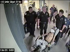FILE - In this Nov. 11, 2015, file frame from jailhouse surveillance video recorded at Denver's Downtown Detention Center, released by the Denver Department of Safety via the law firm Killmer, Lane & Newman, LLP, 50 year-old homeless man Michael Marshall is wheeled out in a restraint chair by Denver sheriff's deputies during a psychotic episode in which a "spit mask" was placed over his face after he vomited. He choked on his vomit and suffocated. Attorneys representing Marshall's family say they have reached a proposed $4.6 million settlement with the city in his death. (Denver Department of Safety/Killmer, Lane & Newman, LLP via AP, File)