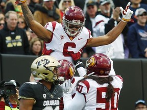 USC wide receiver Michael Pittman Jr., back top, raises his arms after his touchdown catch as center Nico Falah, back center, and linebacker Connor Murphy, back right, join in the celebration as Colorado defensive back Isaiah Oliver, front, walks away in the first half of an NCAA college football game Saturday, Nov. 11, 2017, in Boulder, Colo. (AP Photo/David Zalubowski)