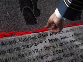 Military member puts a poppy on the ledge of B.C. Afghanistan Memorial, an 18,000 pound slab of granite honouring Canadian soldiers and civilians who served in Afghanistan is unveiled during a dedication ceremony in Victoria, B.C., on Saturday, September 30, 2017. THE CANADIAN PRESS/Chad Hipolito