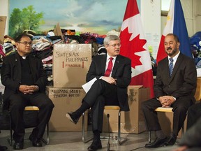 Then Prime Minister Stephen Harper announces further Canadian support for the Philippines in the wake of Typhoon Haiyan alongside Ben Ebcas of the Our Lady of the Assumption Catholic Parish, left, and Senator Tobias Enverga, right, in Toronto on Nov. 18, 2013.