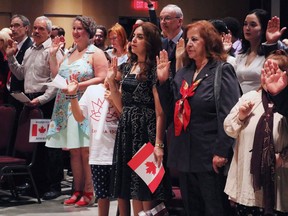 People take the citizenship oath at Pier 21 immigration centre in Halifax on Saturday, July 1, 2017. How many newcomers Canada will admit next year - and in the years ahead - will be revealed Wednesday as the federal immigration minister puts forward his plan. THE CANADIAN PRESS/Adina Bresge