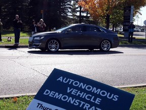 People watch as an autonomous car drives down an Ottawa street as the City of Ottawa and Blackberry QNX demonstrate the vehicle, Thursday, October 12, 2017, in Ottawa. Experts attending an international convention on intelligent transport systems say the increasingly interconnected world is good news for motorists. THE CANADIAN PRESS/Fred Chartrand