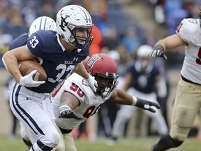 Yale running back Zane Dudek, left, runs against the Harvard during an NCAA college football game on Saturday, Nov. 18, 2017 in New Haven, Conn. Yale won 24-3, securing the Bulldogs' first outright Ivy League championship in 37 years. (AP Photo/Gregory Payan)