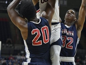 Connecticut's Jalen Adams, center, is fouled by Queens College's Issac Grant, left, as Queens College's Hasan Ringer, right, defends in the first half of an NCAA college exhibition basketball game, Sunday, Nov. 5, 2017, in Storrs, Conn. (AP Photo/Jessica Hill)