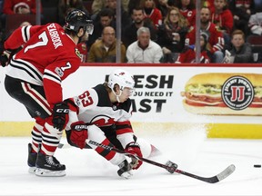 New Jersey Devils left wing Jesper Bratt (63) keeps the puck away from Chicago Blackhawks defenseman Brent Seabrook (7) during the first period of an NHL hockey game Sunday, Nov. 12, 2017, in Chicago. (AP Photo/Kamil Krzaczynski)