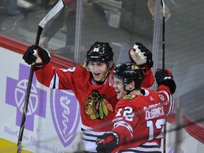 Chicago Blackhawks' Alex DeBrincat (12) celebrates with teammate Patrick Kane (88) after scoring a goal during the second period of an NHL hockey game against the Anaheim Ducks, Monday, Nov. 27, 2017, in Chicago. (AP Photo/Paul Beaty)