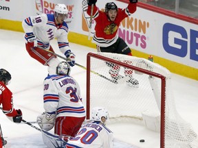 Chicago Blackhawks' Alex DeBrincat, top, celebrates his goal after the puck slowly rolled into the net from between the legs of New York Rangers goalie Henrik Lundqvist as Marc Staal (18) and Chris Kreider (20) watch during the second period of an NHL hockey game, Wednesday, Nov. 15, 2017, in Chicago. (AP Photo/Charles Rex Arbogast)