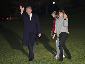 President Donald Trump, left, waves as he walks with first lady Melania Trump, right, and their son Barron Trump on the South Lawn of the White House in Washington, Sunday, Nov. 26, 2017, after returning from Palm Springs, Fla., where they spent the Thanksgiving holiday. (AP Photo/Susan Walsh)