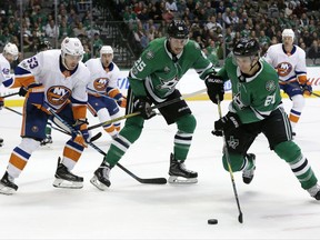 New York Islanders' Casey Cizikas (53) and Dallas Stars' Brett Ritchie (25) watch as left wing Antoine Roussel (21), of France, makes away with the puck during an offensive possession in the first period of an NHL hockey game, Friday, Nov. 10, 2017, in Dallas. (AP Photo/Tony Gutierrez)