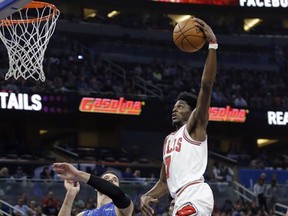 Chicago Bulls' Justin Holiday, right, goes over Orlando Magic's Nikola Vucevic (9) for a dunk during the first half of an NBA basketball game, Friday, Nov. 3, 2017, in Orlando, Fla. (AP Photo/John Raoux)