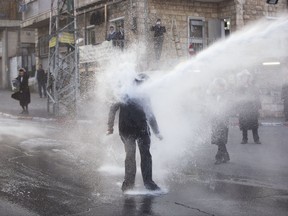 FILEile - In this Wednesday, March. 15 , 2017 file photo, an ultra-Orthodox Jew gets hit by a police water canon during a protest against Israeli army conscription in Jerusalem. A string of protests by ultra-Orthodox Jewish activists against Israel's compulsory military service has paralyzed Jerusalem in recent weeks in what their leaders had hoped would be a show of strength by the traditionally insular society. (AP Photo/Oded Balilty, File)