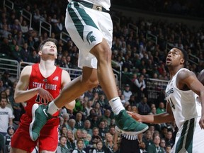 Michigan State's Miles Bridges (22) dunks off an alley-oop against Stony Brook's Jordan McKenzie, left, during the first half of an NCAA college basketball game, Sunday, Nov. 19, 2017, in East Lansing, Mich. (AP Photo/Al Goldis)