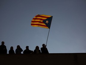A man holds an independence flag on top of a building as demonstrators take part at a protest calling for the release of Catalan jailed politicians, in Barcelona, Spain, on Saturday, Nov 11, 2017. Eight members of the now-defunct Catalan government remain jailed in a related rebellion case. Former regional president Carles Puigdemont and four other ex-cabinet members fled to Belgium where they are fighting extradition. (AP Photo/Emilio Morenatti)