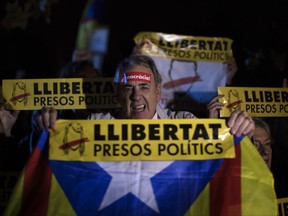 Demonstrators holding banners reading in Catalan "freedom for the political prisoners" gather outside the Catalonian Parliament to protest against the decision of a judge to jail ex-members of the Catalan government, in Barcelona, Spain, Thursday, Nov. 2, 2017. A Spanish judge has ordered nine ex-members of the government in Catalonia jailed while they are investigated on possible charges of sedition, rebellion and embezzlement. (AP Photo/Emilio Morenatti)