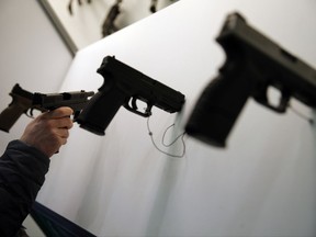 A visitor handles a gun displayed at the 20th Paris Milipol, the worldwide exhibition dedicated to homeland security, in Villepinte, north of Paris , Tuesday, Nov. 21, 2017. (AP Photo/Christophe Ena)