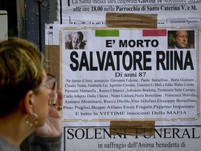 A woman looks at a funeral poster with the list of main Mafia victims, including slain anti-Mafia magistrates Giovanni Falcone and Paolo Borsellino whose photos top the poster, announcing Toto' Riina's death, in Ercolano, near Naples, southern Italy, Friday, Nov. 17, 2017. Sicilian mafia 'boss of bosses,' Salvatore Toto' Riina, one of Italy's most feared mobsters, died at the age of 87 on Nov. 17, in a prison section in Parma. He was serving 26 life sentences. (Ciro Fusco/ANSA via AP)