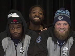 Jamal Campbell (centre) peeks between fellow Toronto Argonauts offensive linemen D.J. Sackey (left) and Chris Van Zeyl at Grey Cup media day in Ottawa on Nov. 23.