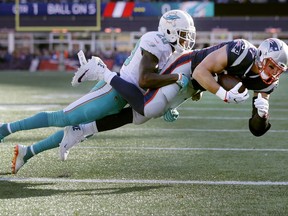 New England Patriots tight end Rob Gronkowski, right, scores a touchdown with Miami Dolphins safety Reshad Jones on his back during the first half of an NFL football game, Sunday, Nov. 26, 2017, in Foxborough, Mass. (AP Photo/Steven Senne)