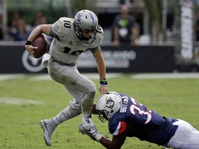 Central Florida quarterback McKenzie Milton (10) tries to evade a tackle by Connecticut linebacker Chris Britton, right, during the first half of an NCAA college football game, Saturday, Nov. 11, 2017, in Orlando, Fla. (AP Photo/John Raoux)